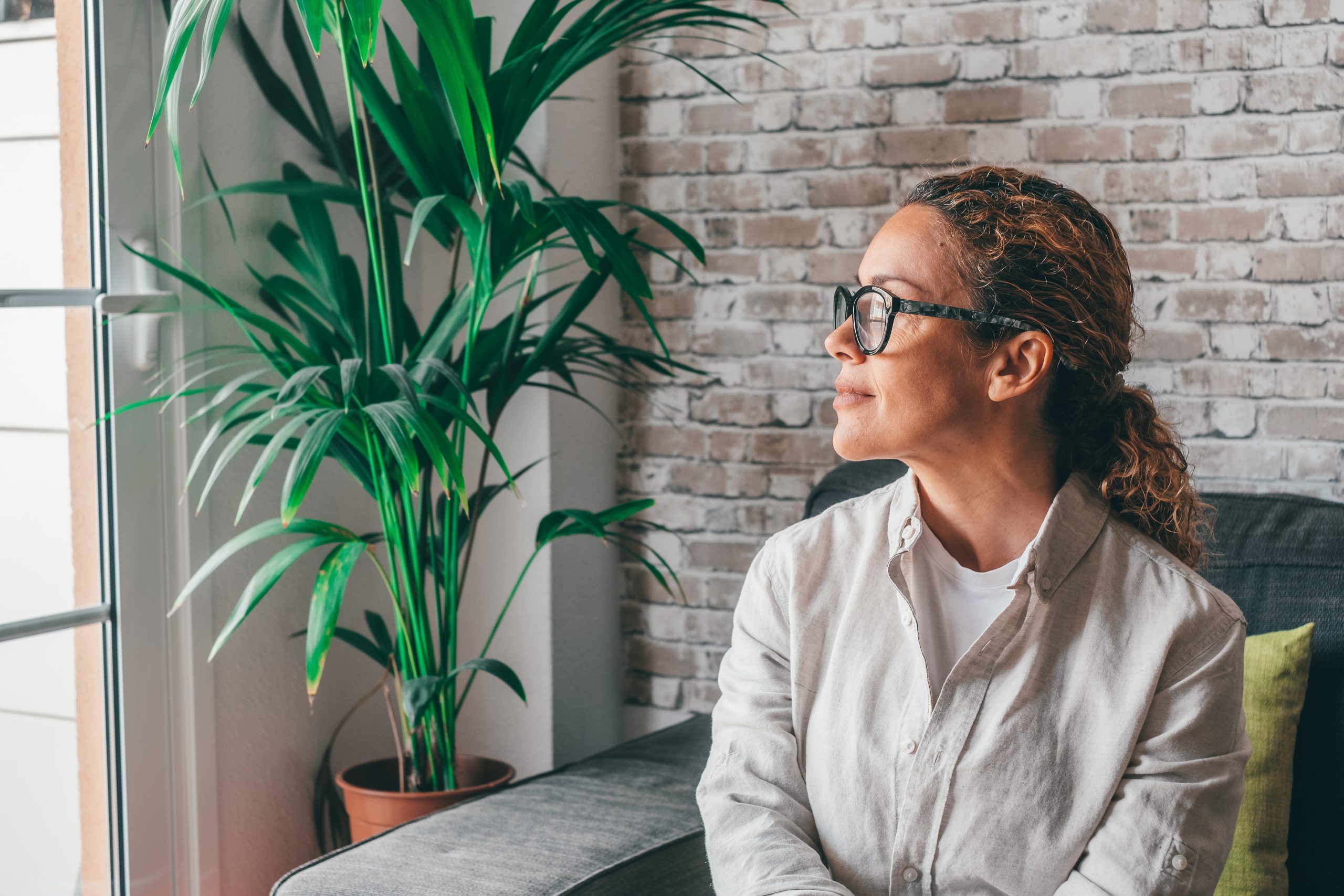 Happy thoughtful millennial business woman in casual looking at window with pensive dreamy smile, thinking of work project future vision, ambitious career, planning goals. Head shot portrait